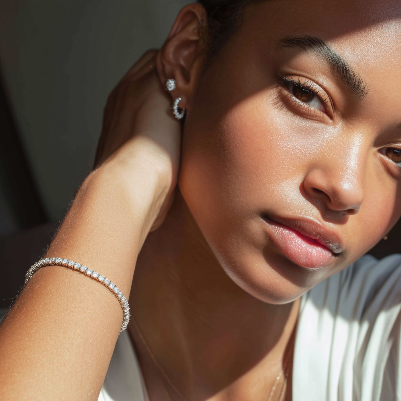 A model in soft natural light wearing a diamond tennis bracelet, hoop earring catching the sun